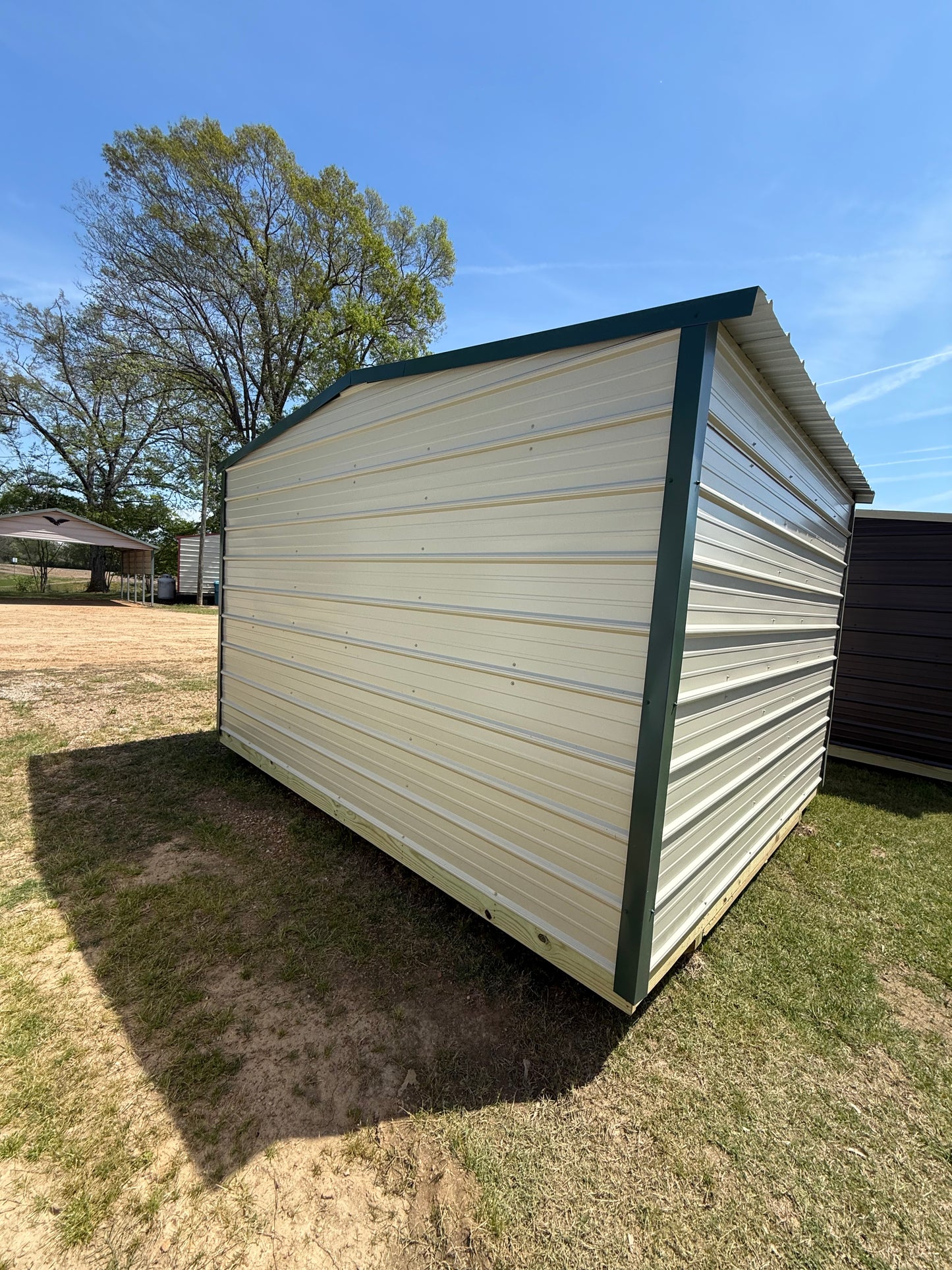 back/side view of 10x12 regular roof portable building light stone/hunter green 